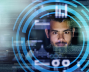 A man looks at a computer screen with digital data overlays and circular graphic elements, suggesting a focus on technology or cybersecurity.