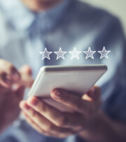 A person holding a smartphone with five white stars displayed above it, suggesting a rating or review process.
