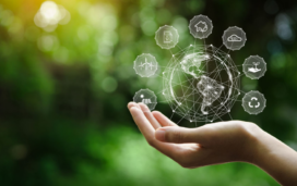 A hand holds a digital globe surrounded by environmental and sustainability icons, symbolizing eco-friendly technologies and global responsibility.