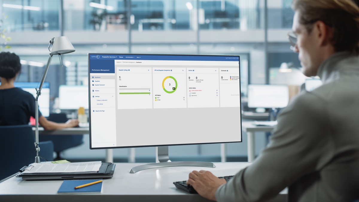 Person sitting at a desk in a modern office, viewing a performance management dashboard on a computer monitor.