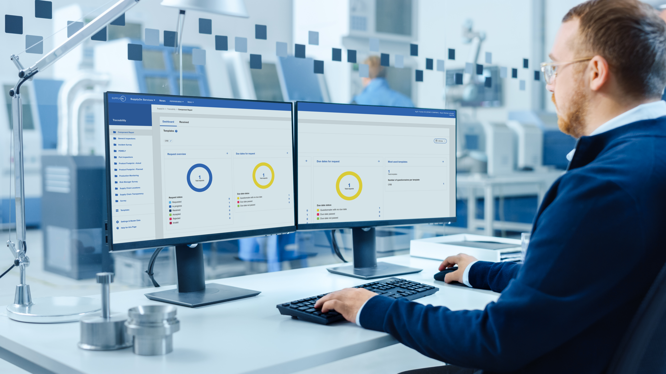 A person working at a desk with two computer monitors displaying data dashboards in a modern office or lab environment.
